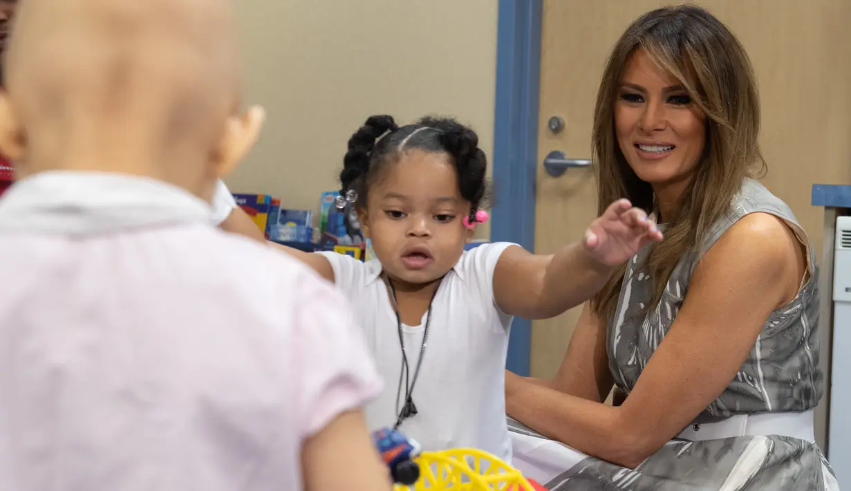 Ibu Negara AS, Melania Trump bermain dengan pasien anak, Natalayah Fields saat mengunjungi Rumah Sakit Anak Monroe Carell Jr. di Nashville, Selasa (24/7). Kedatangan Melania untuk berdiskusi terkait Neonatal Abstinence Syndrome (NAS). (AFP/SAUL LOEB)