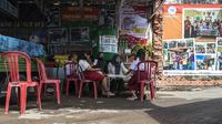 Seorang perempuan dari organisasi pemuda setempat membantu siswa bersekolah secara virtual di tempat pembuangan sampah yang menyediakan WiFi gratis, di Surabaya, Rabu (15/9/2021). Belajar secara virtual itu sudah berjalan lebih dari setahun lebih di tengah pandemi Covid-19. (JUNI KRISWANTO/AFP)