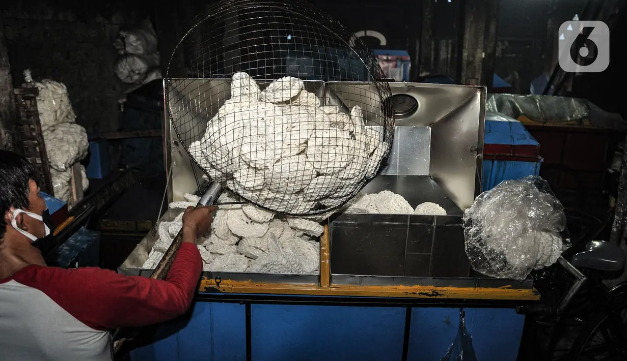 Pekerja memasukkan kerupuk yang telah dimasak ke dalam tempat penjualan di industri rumahan kawasan Cipinang Melayu, Jakarta, Selasa (16/2/2021). Selama pandemi corona, jumlah produksi di industri rumahan ini dikurangi dari 10.000 menjadi 5.000 kerupuk tiap harinya. (merdeka.com/Iqbal S Nugroho)