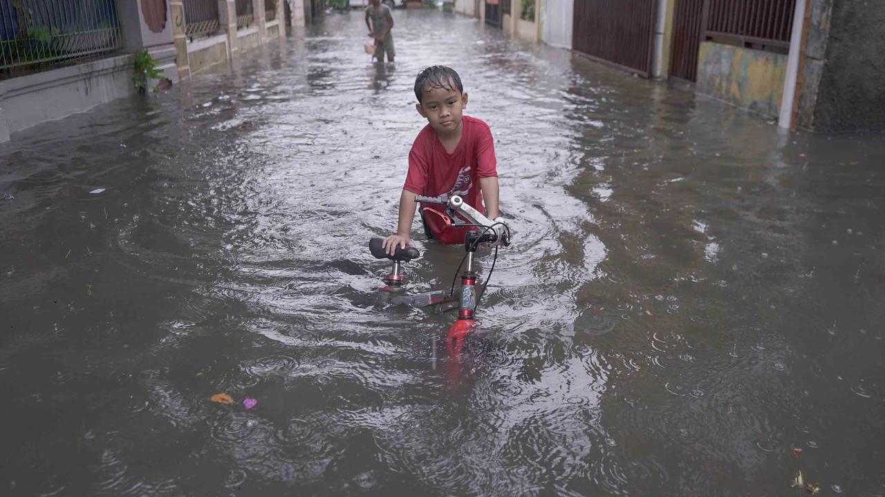 FOTO: Drainase Meluap, Warga Pasar Rebo Terobos Genangan