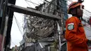 Petugas Basarnas berdiri dekat gedung yang ambruk di Jalan Brigjen Katamso, Kota Bambu Selatan, Palmerah, Jakarta Barat, Senin (6/1/2020). Tiga orang dilaporkan terluka akibat tertima material gedung empat lantai tersebut. (Liputan6.com/Johan Tallo)
