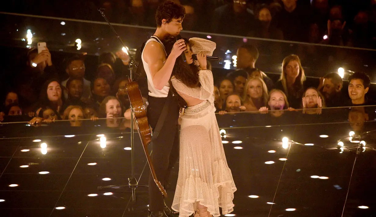 Shawn Mendes dan Camila Cabello saat tampil di atas panggung MTV VMA's 2019 di New Jersey, AS (26/8/2019). Shawn Mendes muncul dengan kaos putih ketat tanpa lengan, memainkan gitarnya. (Bryan Bedder/Getty Images/AFP)