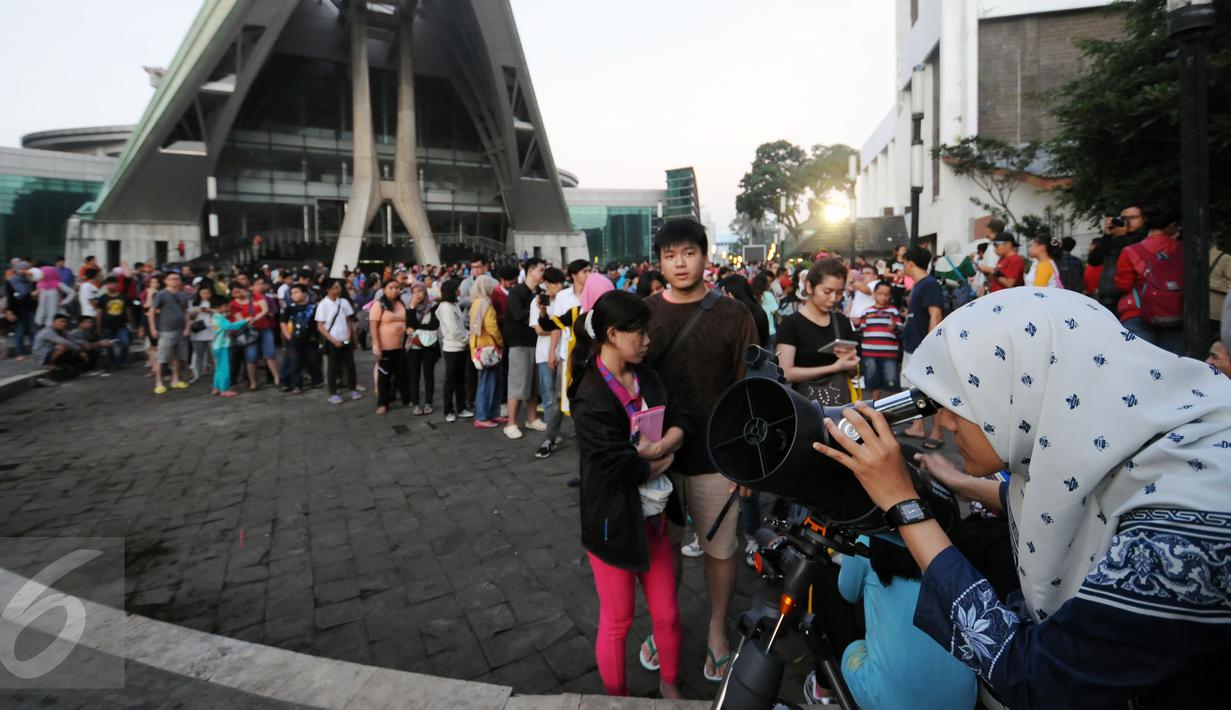 Ratusan warga antri menggunakan teleskop untuk melihat proses gerhana matahari di sekitar Taman Ismail Marzuki, Jakarta, Rabu (9/3/2016). Di Jakarta, fenomena gerhana matahari 90% bisa diamati selama 2,11 menit. (Liputan6.com/Helmi Fithriansyah)   