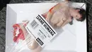 Seorang aktivis wanita pembela hak-hak hewan, dibungkus dalam kemasan berlabel 'Carne Humana' (daging manusia) saat menggelar aksi protes konsumsi daging dan mempromosikan vegetarian di Barcelona, Spanyol, Minggu (22/5/2016). (REUTERS / Albert Gea)
