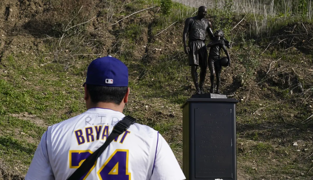 Oscar Romero berdiri dekat patung untuk mengenang Kobe Bryant dan putrinya, Gianna di Calabasas, California, Rabu (26/1/2022). Patung itu dibawa seniman Dan Medina, di jalan setapak dekat lokasi Bryant, putrinya dan tujuh orang lainnya tewas dalam kecelakaan helikopter pada 2020. (AP/Ashley Landis)