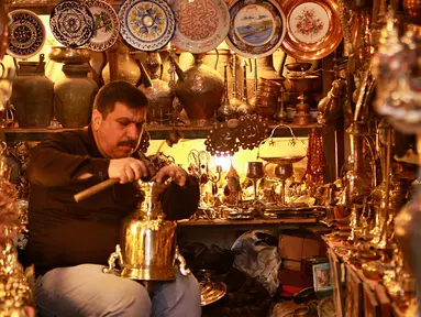 Pedagang barang antik Saadoun Mansouri bekerja di tokonya di Baghdad, Irak, Rabu (20/3). (AP Photo/Hadi Mizan)