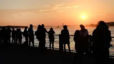 Sejumlah warga menikmati taman Brooklyn saat matahari terbenam di mana suhu mencapai hampir 70 derajat di New York City (21/2). Cuaca New York akan berubah kembali ke musim dingin dengan suhu yang diperkirakan 30 derajat. (AFP Photo/Spencer Platt)