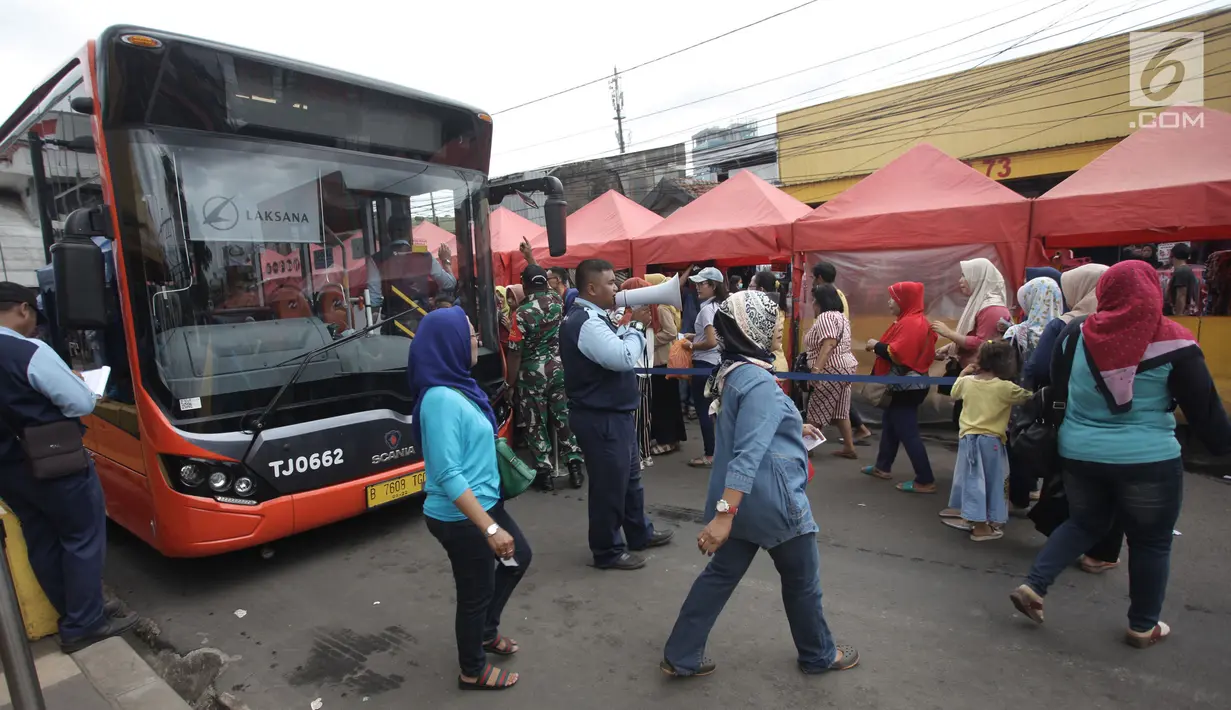 Petugas TransJakarta dengan pengeras suara memberitahukan informasi operasi bus Tanah Abang Explorer di Jalan Jatibaru, Tanah Abang, Jakarta, Sabtu (3/2). Bus Tanah Abang Explorer pagi ini sudah mulai kembali beroperasi lagi. (Liputan6.com/Arya Manggala)