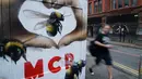 Seorang pria berjalan melewati grafiti di dinding yang menggambarkan lebah di Manchester (28/5). Sebelumnya, serangan bom yang terjadi saat konser Ariana Grande menyebabkan 22 orang tewas dan melukai 119 lainnya. (AP Photo/Mstyslav Chernov)