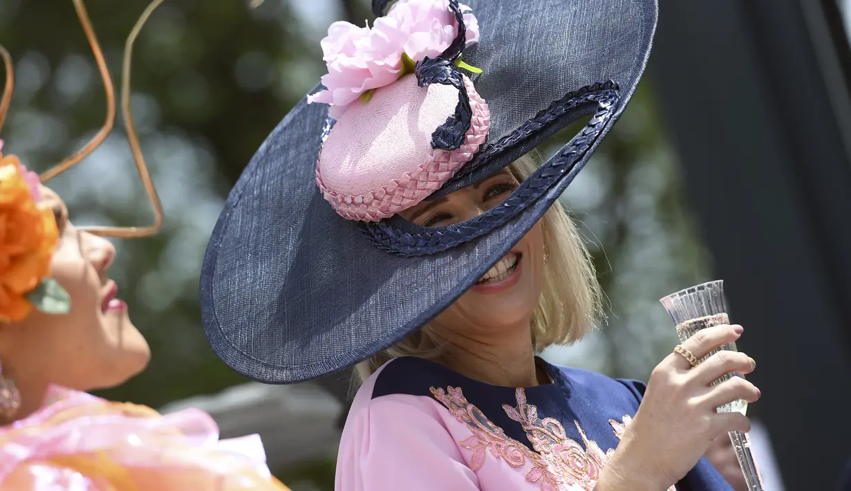 Seorang wanita tertawa sebelum pertandingan pacuan kuda Piala Melbourne di Melbourne (5/11/2019). Para wanita tampil cantik dan modis dengan hiasan kepala yang mereka gunakan selama menyaksikan balap kuda di Melbourne Cup.  (AFP Photo/William West)