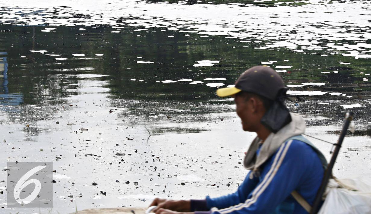 Warga melintasi kali yan tertutup limbah busa, Jakarta, Selasa (16/2). Buruknya tata kelola air di Ibukota menjadi penyebab kondisi Kali Ancol selalu dipenuhi limbah busa, yang merupakan indikator pencemaran air. (Liputan6.com/Immanuel Antonius)
