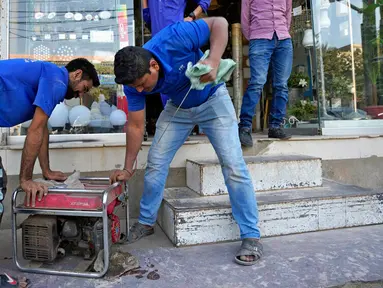 Seorang penjaga toko menyalakan generator listrik menyusul gangguan listrik nasional di sebuah toko di Karachi, Pakistan, Senin (23/1/2023). Pakistan mengalami pemadaman listrik skala nasional pada hari ini. (AP Photo/Fareed Khan)