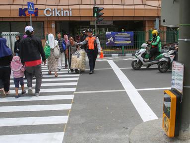 Pejalan kaki melintasi penyeberangan pejalan kaki yang dikontrol lampu lalu lintas atau dikenal sebagai persimpangan pelikan (pelican crossing) di sisi timur Stasiun Cikini, Jakarta, Senin (15/9/2025). (merdeka.com/Arie Basuki)