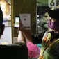 Petugas membantu pengunjung melakukan scan QR code melalui aplikasi PeduliLindungi di Pasar Anyar, Tangerang, Selasa (26/10/2021). PD Pasar Kota Tangerang memberlakukan penerapan aplikasi PeduliLindungi di dua pasar tradisional, yakni Pasar Anyar dan Pasar Poris. (Liputan6.com/Angga Yuniar)