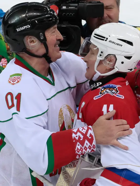 Presiden Rusia Vladimir Putin (kanan) dan Presiden Belarusia Alexander Lukashenko (kiri) berpelukan usai mengikuti pertandingan hoki es di Shayba Arena, Resor Laut Hitam Sochi, Rusia, (15/2). (Sergei Chirikov / Pool / AFP)