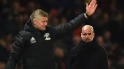 Pelatih Manchester City Pep Guardiola (kanan) dan manajer Manchester United Ole Gunnar Solskjaer saat menyaksikan para pemain mereka bertanding pada laga Liga Inggris di Old Trafford, Manchester, Inggris, Minggu (8/3/2020). Manchester United menang 2-0. (Oli SCARFF/AFP)