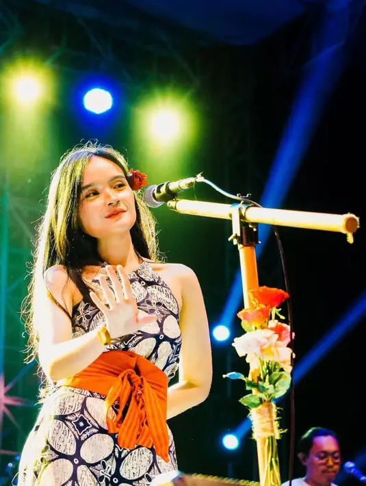Fanny Soegi menggunakan busana bermotif batik dengan tambahan kain dibagian pinggang. Penyanyi keturunan Jawa-Kalimantan ini memiliki stand mic khusus yang dipercantik dengan beberapa tangkai bunga. (Instagram/@fannysoegi)