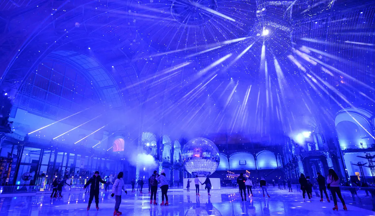Orang-orang berseluncur di arena ice skating di bawah kubah kaca mewah legendaris, Grand Palais, Paris, Selasa (17/12/2019). Arena ice skating musiman ini menjadi yang terbesar di Prancis, dan satu magnet wisata sepanjang tahun. (Photo by Thomas SAMSON / AFP)