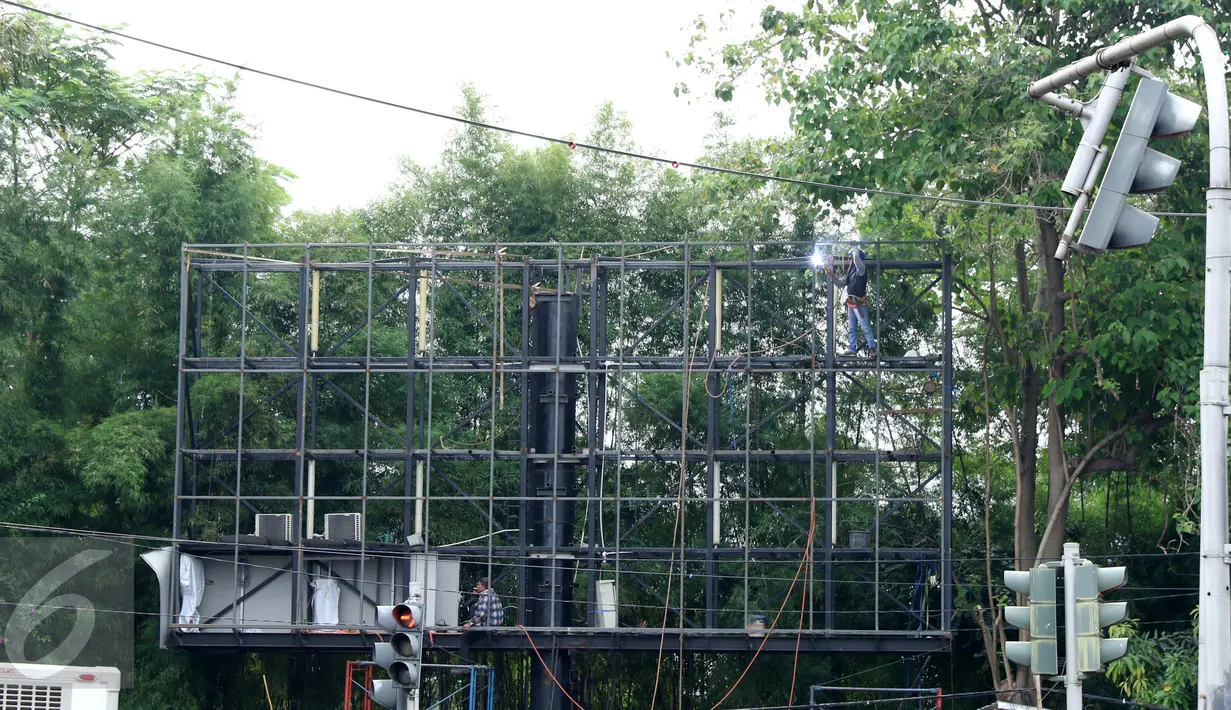 Pekerja memperbaiki papan reklame di Kawasan Senayan Jakarta, Kamis, (6/10). Papan reklame diremajakan agar tidak roboh diterpa hujan deras disertai angin kencang. (Liputan6.com/Gempur M. Surya)