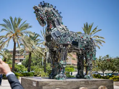 Seorang pria mengambil gambar patung kuda troya bernama "Cyber Horse" yang terbuat dari ribuan komputer dan komponen ponsel yang terinfeksi virus, di pintu masuk konferensi Cyber Week tahunan di Tel Aviv University, Israel, Senin (20/6). (Jack GUEZ/AFP)