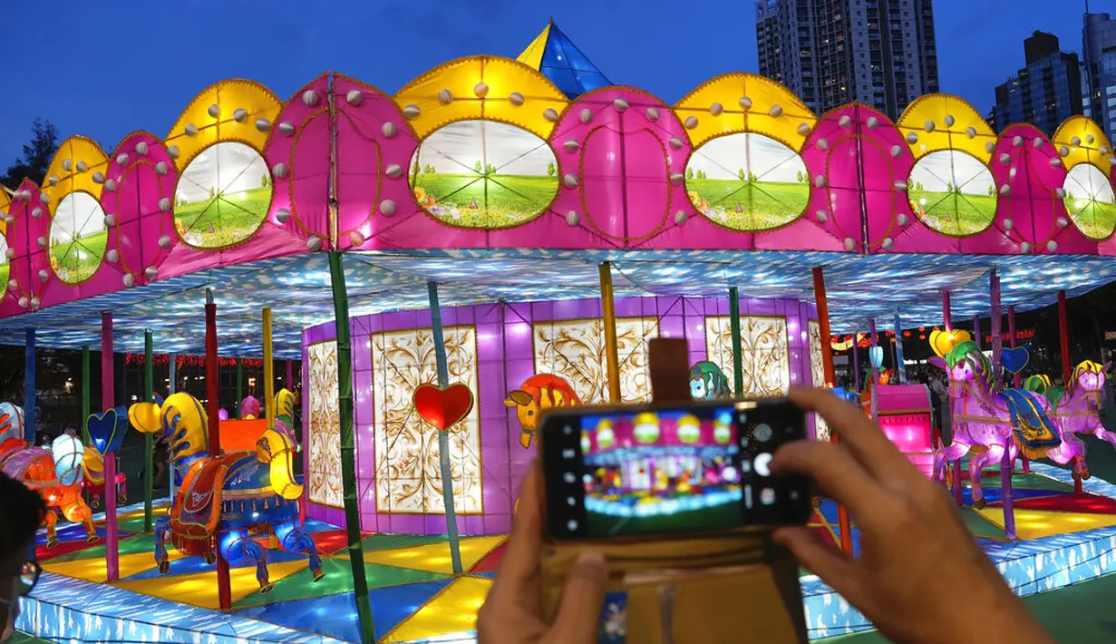 Orang-orang berfoto dengan dekorasi selama Festival Pertengahan Musim Gugur di taman Victoria di Hong Kong, Selasa (21/9/2021).  Festival ini jatuh pada hari ke-15 bulan ke-8 penanggalan Imlek. (AP Photo/Vincent Yu)