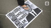 Pengunjuk rasa berdiri di atas poster bergambar Presiden Prancis Emmanuel Macron dalam aksi damai di kawasan Sarinah, Jakarta, Senin (2/11/2020). Massa demonstran dari gabungan elemen Islam mengecam pernyataan presiden Emmanuel Macron yang dianggap menghina Islam. (Liputan6.com/Faizal Fanani)