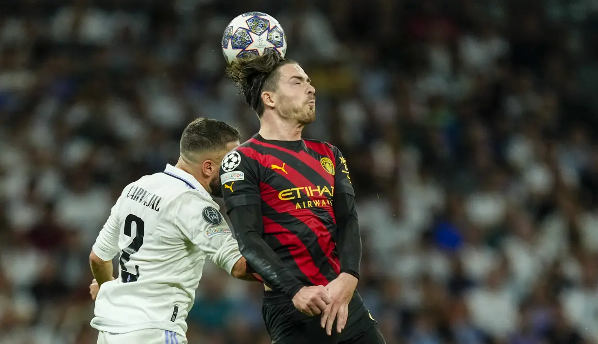 <p>Gelandang Manchester City, Jack Grealish berebut bola udara dengan bek Real Madrid, Dani Carvajal selama pertandingan leg pertama semifinal Liga Champions di stadion Santiago Bernabeu di Madrid, Spanyol, Selasa, 9 Mei 2023. (AP Photo/Jose Breton)</p>