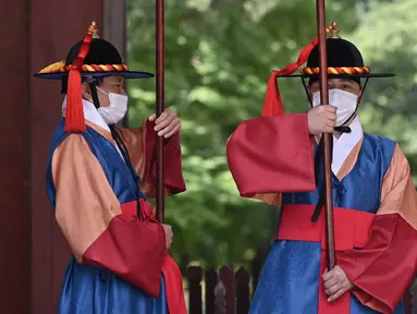 Anggota 'penjaga istana' yang mengenakan masker berdiri untuk turis di gerbang utama Istana Deoksugung di Seoul (4/9/2020). Korea Selatan melaporkan 198 kasus Covid-19 baru pada 4 September, hari ke-22 berturut-turut meningkat tiga digit. (AFP/Jung Yeon-je)