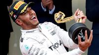 Pemabalap Mercedes Lewis Hamilton memegang pialanya diatas podium usai berhasil menjuarai Grand Prix di Monaco, (29/5). Hamilton menjadi yang tercepat dengan mencatatkan waktu satu jam 59 menit 29,133 detik. (REUTERS/Eric Gaillard)