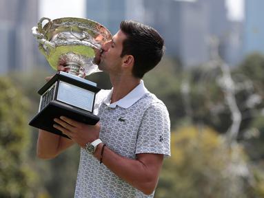 Petenis Serbia, Novak Djokovic mencium piala juara tunggal putra Australia Terbuka 2020 saat sesi pemotretan di Royal Botanic Gardens Victoria, Melbourne, Australia, Senin (3/2/2020). Bagi Novak Djokovic, ini merupakan gelar Australia Terbuka kedelapan. (AP Photo/Dita Alangkara)