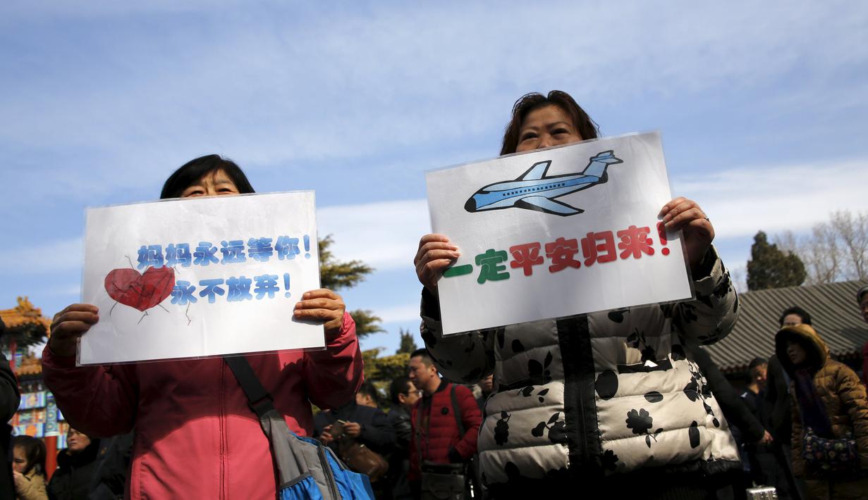 Anggota keluarga penumpang pesawat Malaysia Airlines MH370 berunjuk rasa membawa poster di Lama Temple, Beijing, Cina, (8/3). Poster Tersebut bertuliskan "Ibu akan selalu menunggu. Tidak akan menyerah." (REUTERS/Kim Kyung-hoon)