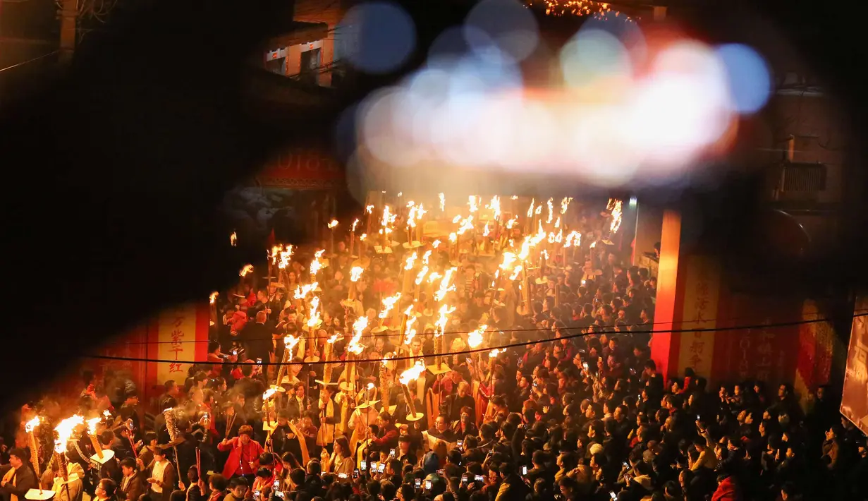 Ratusan warga memegang obor mengikuti parade untuk berdoa semoga berhasil di tahun baru saat sebuah festival obor di Jinjiang di provinsi Fujian, China timur (24/2). (AFP Photo)