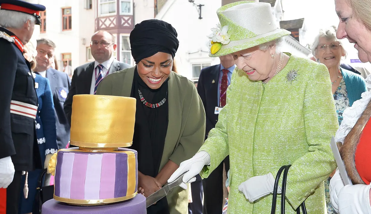 Wajah bahagia Ratu Inggris Elizabeth II saat memotong kue yang ditemani oleh Nadiya Husein pada perayaan hari ulang tahunnya ke-90 di Istana Windors, Berkshire, Inggris (21/4/2016). (AFP PHOTO/John Stillwell)