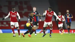 Pemain Crystal Palace Jordan Ayew (kiri) mencoba menghentikan pemain Arsenal Thomas Partey pada pertandingan Liga Inggris di Emirates Stadium, London, Inggris, Kamis (14/1/2021). Pertandingan berakhir imbang 0-0. (Julian Finney/Pool via AP)