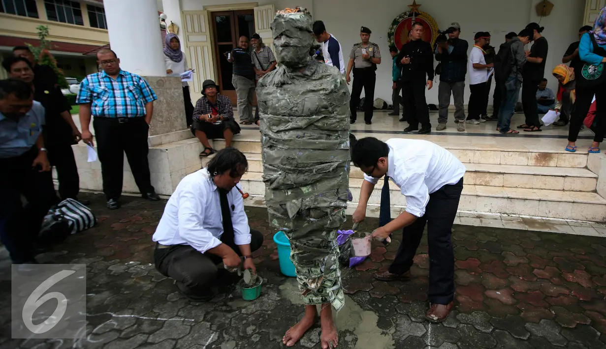 Seorang pengunjukrasa dari Aliansi Masyarakat Peduli Tata Ruang Yogyakarta megelar aksi teatrikal  manusia semen di Gedung DPRD DIY, (29/2). Mereka menuntut keseimbangan dalam fungsi dan kepemilikan ruang dengan masyarakat. (Liputan6.com/Boy Harjanto)