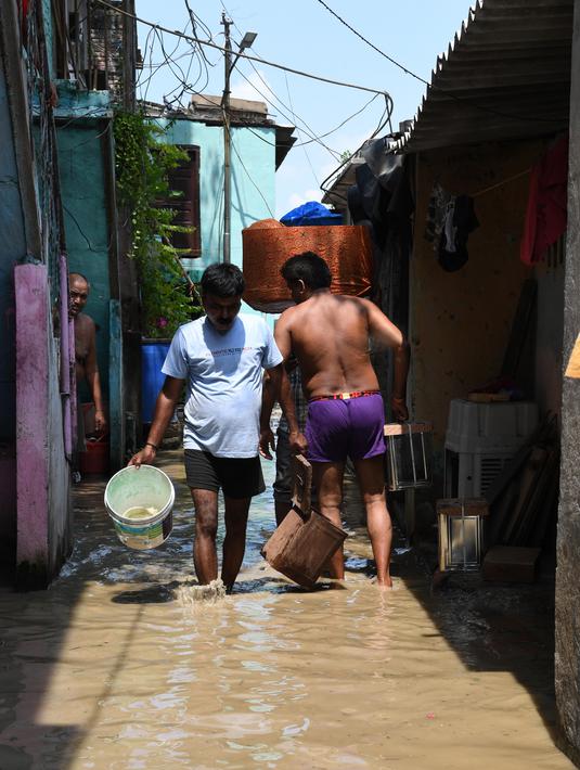 Sejumlah warga mengeluarkan air dari rumah mereka saat banjir melanda perumahan dekat tepi Sungai Yamuna yang meluap di New Delhi, India, Selasa (20/8/2019). (AFP Photo/Sajjad Hussain)