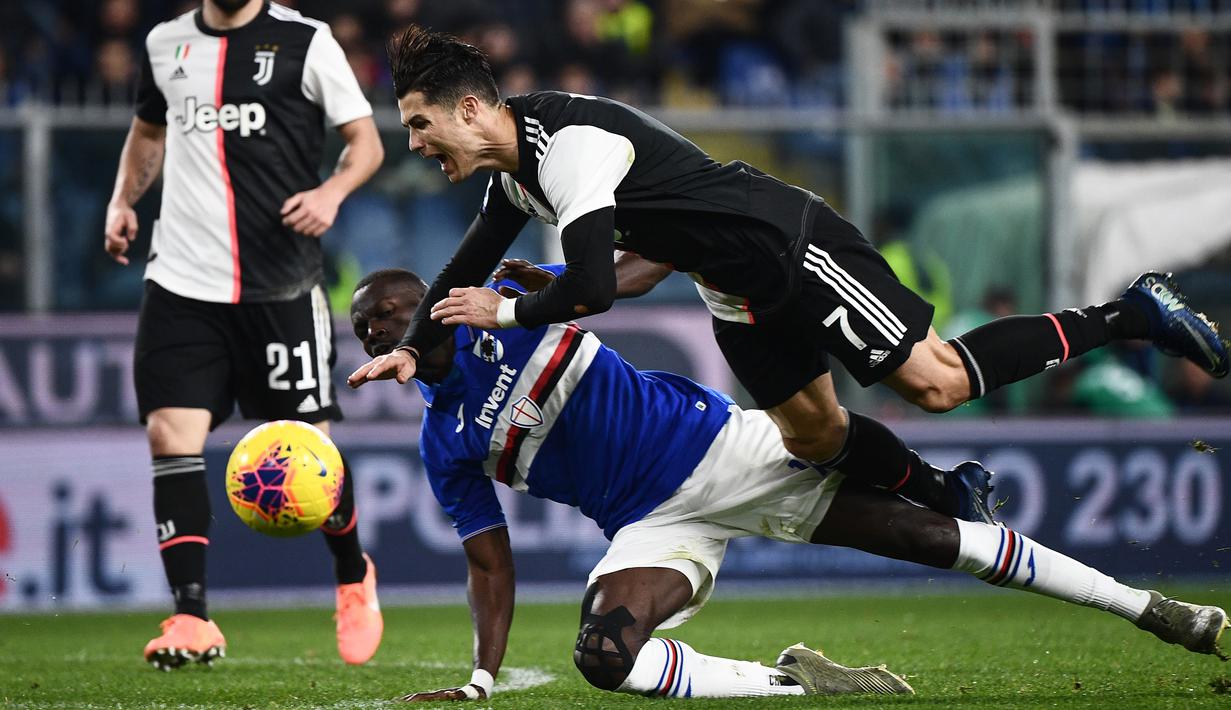 Striker Juventus, Cristiano Ronaldo, terjatuh saat berebut bola dengan bek Sampdoria, Omar Colley pada laga Serie A 2019 di Stadion Luigi Ferraris, Rabu (18/12). Juventus menang 2-1 atas Sampdoria. (AFP/Marco Bertorello)