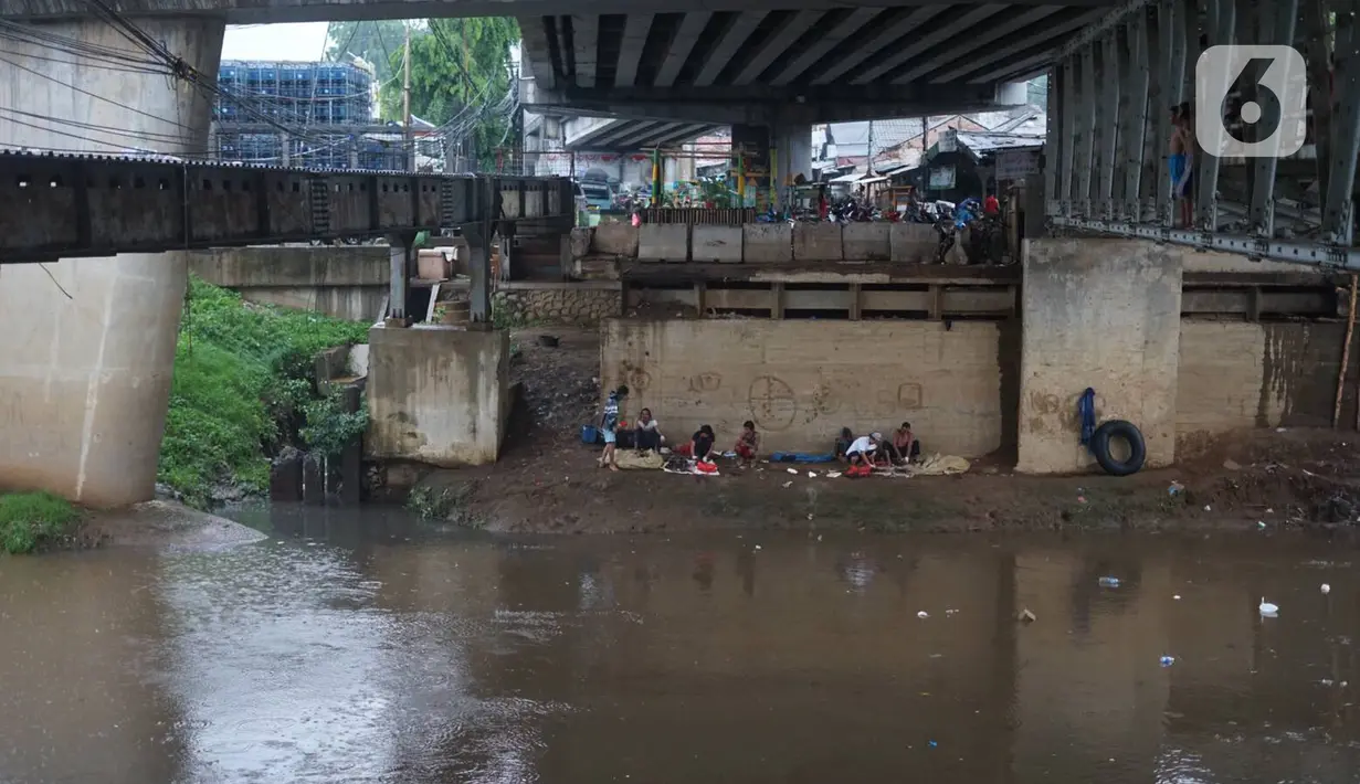 Sejumlah orang terlihat duduk di pinggir aliran Sungai Ciliwung kawasan Rawajati, Jakarta, Selasa (17/12/2019). Hujan deras yang mengguyur Jakarta sejak siang menyebabkan debit air Sungai Ciliwung mulai mengalami kenaikan, namun masih terpantau normal. (Liputan6.com/Immanuel Antonius)
