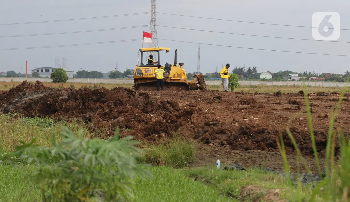 Petugas dari Dinas Bina Marga menggunakan kendaraan alat berat saat menyelesaikan penggarapan lahan untuk dijadikan lokasi pemakaman khusus Covid-19 di Rorotan, Jakarta Utara, Selasa (5/1/2021). Pemprov DKI menyiapkan 1.500 lubang makam khusus COVID-19 di TPU Rorotan. (Liputan6.com/Herman Zakharia)