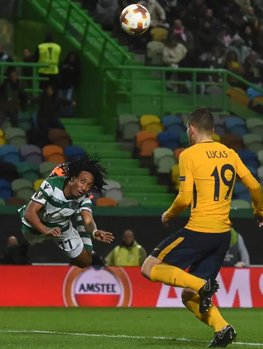 Pemain Sporting CP, Gelson Martins menyundul bola di samping bek Atletico Madrid Lucas Hernandez pada leg kedua perempat final Liga Europa di Estadio Jose Avalade, Jumat (13/4). Atletico Madrid tetap maju ke semifinal meski kalah 0-1 (FRANCISCO LEONG/AFP)