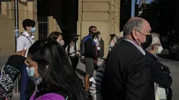 Pejalan kaki yang memakai masker menunggu untuk menyeberang jalan di pusat kota Santiago, Chili, Rabu (5/4/2022). Chile akan melonggarkan aturan protokol kesehatan Covid-19 pada 14 April dan berhenti mewajibkan penggunaan masker di ruang terbuka. (AP Photo/Esteban Felix)