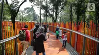 Pengunjung melintasi jembatan di Tebet Eco Park, Jakarta, Selasa (10/5/2022). Warga memanfaatkan libur dengan bermain dan berolahraga di taman terbuka setelah pemerintah memperpanjang masa liburan sekolah hingga tanggal 11 Mei 2022. (Liputan6.com/Faizal Fanani)