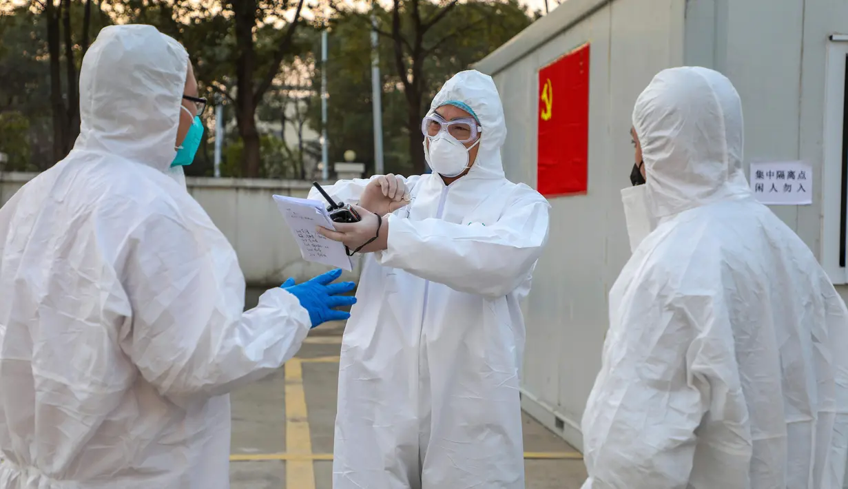 Para pekerja berpakaian pelindung berbincang di luar hotel yang digunakan dalam isolasi medis virus corona di Wuhan, Provinsi Hubei, China, Senin (3/2/2020). (Chinatopix via AP)