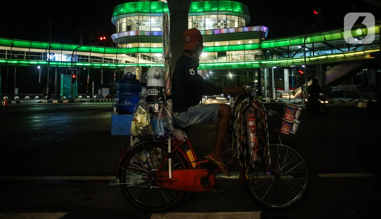 Pedagang melihat halte CSW yang berhiaskan lampu warna-warni di Kawasan Kebayoran Baru, Jakarta, Kamis (5/8/2021). Konsep desain Cakra Selaras Wahana tersebut memiliki arti sebagai lingkaran penghubung yang setara antar moda. (Liputan6.com/Johan Tallo)