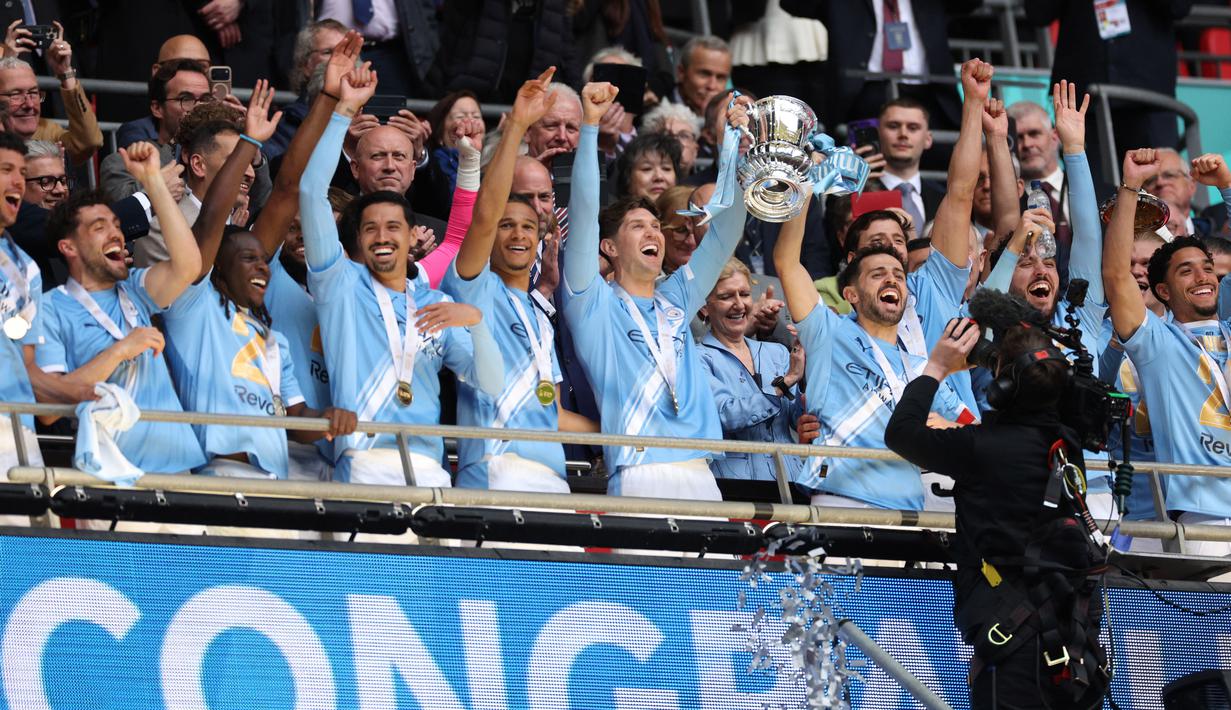 Para pemain Manchester City merayakan gelar Piala FA setelah mengalahkan Chelsea dengan skor 1-0 di partai final di Wembley Stadium hari Sabtu (16/05/2026) malam WIB. (AFP/Adrian Dennis)