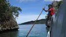 Seorang anak laki-laki dari suku Byak Betew membantu menggerakkan kapal untuk membawa pengunjung ke pulau Raja Ampat 20 Agustus 2017. Raja Ampat merupakan rumah bagi sekitar 1.400 jenis ikan dan 600 spesies karang. (AFP Photo/Goh Chai Hin)