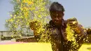 Pekerja menaburkan bubuk warna herbal yang ramah lingkungan untuk dikeringkan yang akan digunakan pada festival Holi di sebuah pabrik di pinggiran Ahmedabad, India (7/3). (AFP Photo/ Sam Panthaky)