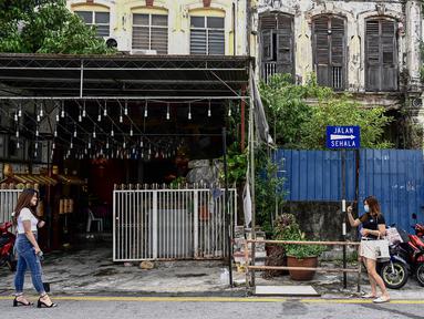 Turis lokal mengambil foto di sepanjang kawasan tua di Penang (1/8/2020). Malaysia tengah memperingatkan gelombang kedua virus corona COVID-19. (AFP Photo/Goh Chai Hin)