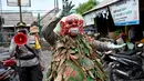 Polisi mengenakan topeng menyeramkan yang disebut "Leak" saat sosialisasi encegahan COVID-19 di pasar tradisional di Kerobokan, Denpasar, Kamis (14/5/2020). Kegiatan itu mengimbau masyarakat agar selalu mengenakan masker, rutin mencuci tangan, menjaga jarak, serta tidak mudik. (SONNY TUMBELAKA/AFP)