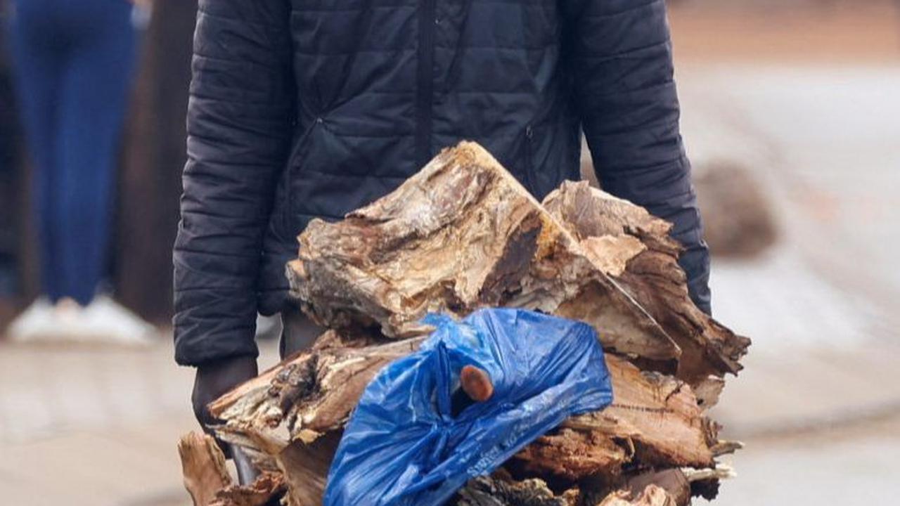 Seorang pria berjalan mendorong gerobak berisi kayu bakar saat mereka bersiap menghadapi kondisi cuaca beku di Protea South, di luar Johannesburg di Afrika Selatan.